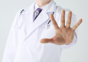 医師が手を広げてこちらに向け、注意喚起している画像